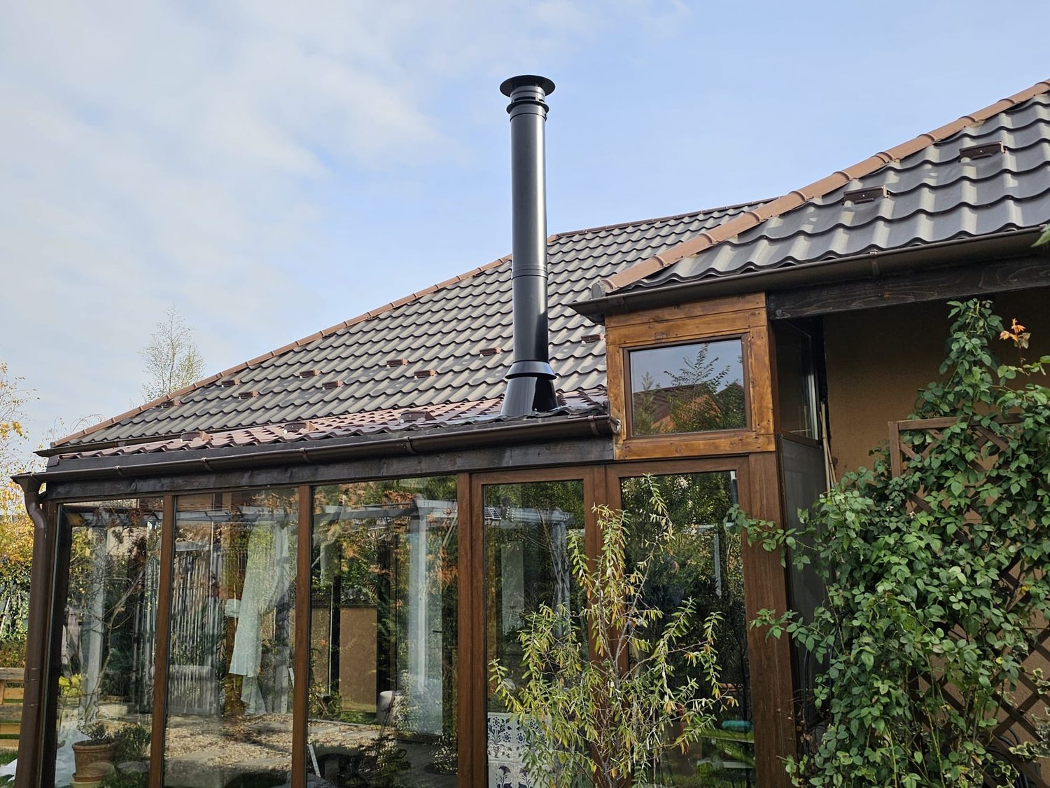 Coș de fum din inox montat la o locuință cu verandă din lemn